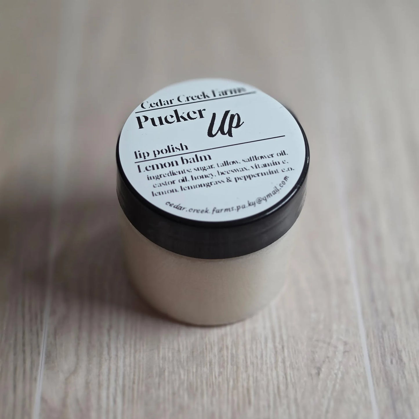Cedar Creek Farms Pucker Up lip polish lemon balm jar, natural lip scrub in small container on wood surface
