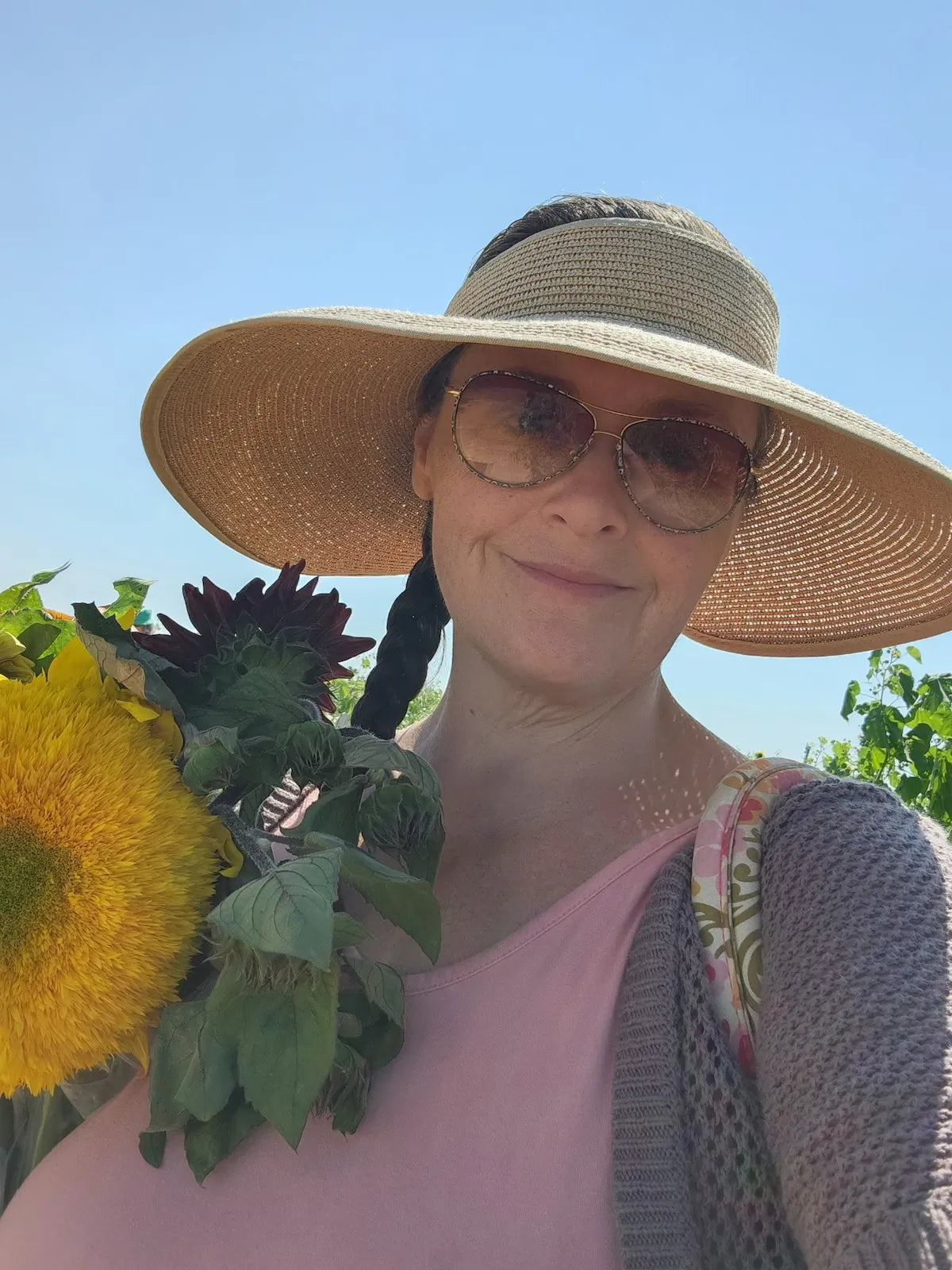Heather from Cedar Creek Farms holding sunflowers outdoors representing natural ingredients and farm sourced skincare products