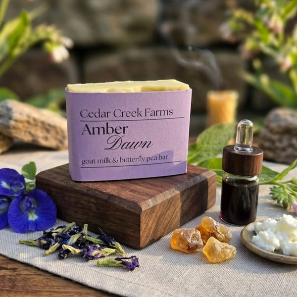Cedar Creek Farms Amber Dawn goat milk and butterfly pea soap bar with dried flowers and botanical ingredients on wooden display