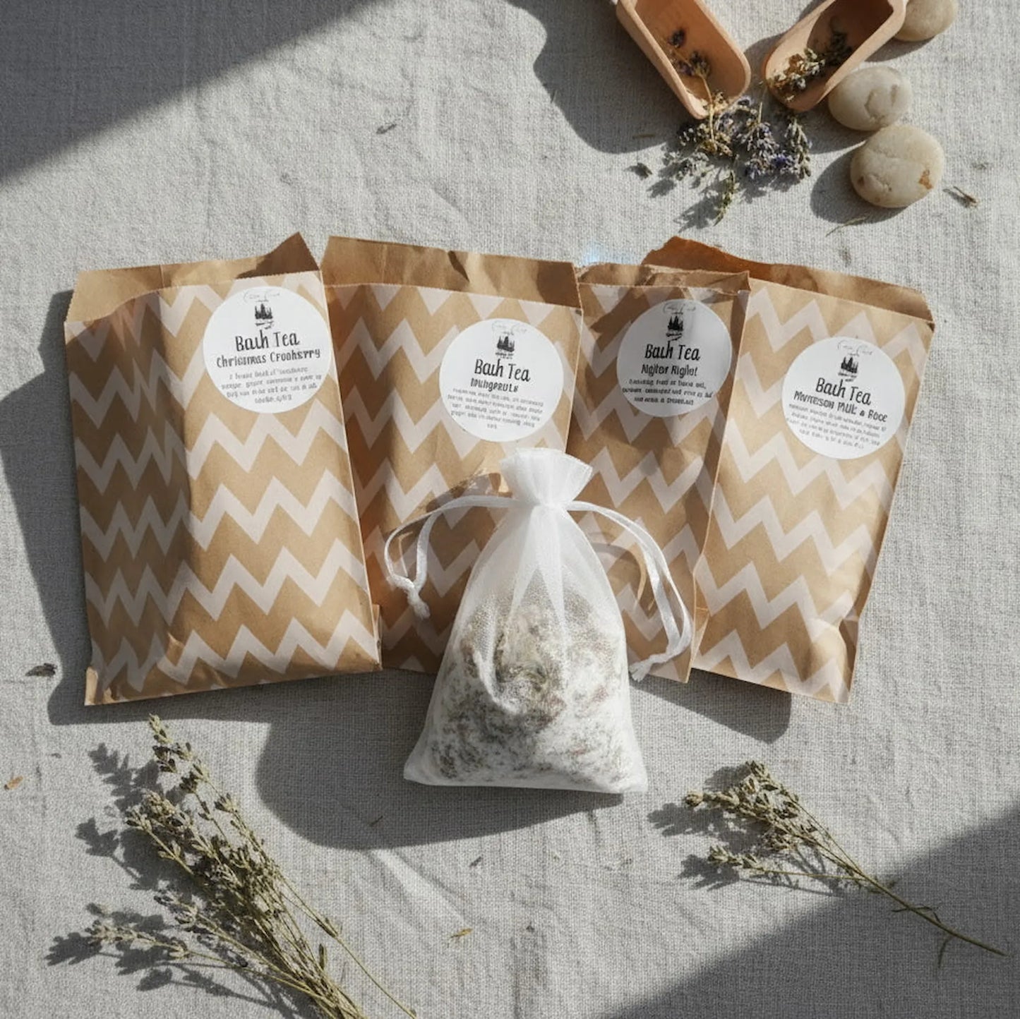 Cedar Creek Farms assorted bath tea set flat lay featuring multiple botanical bath tea blends in kraft packaging with a muslin tea bag and dried herbs on linen background