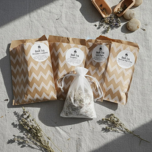 Cedar Creek Farms assorted bath tea set flat lay featuring multiple botanical bath tea blends in kraft packaging with a muslin tea bag and dried herbs on linen background
