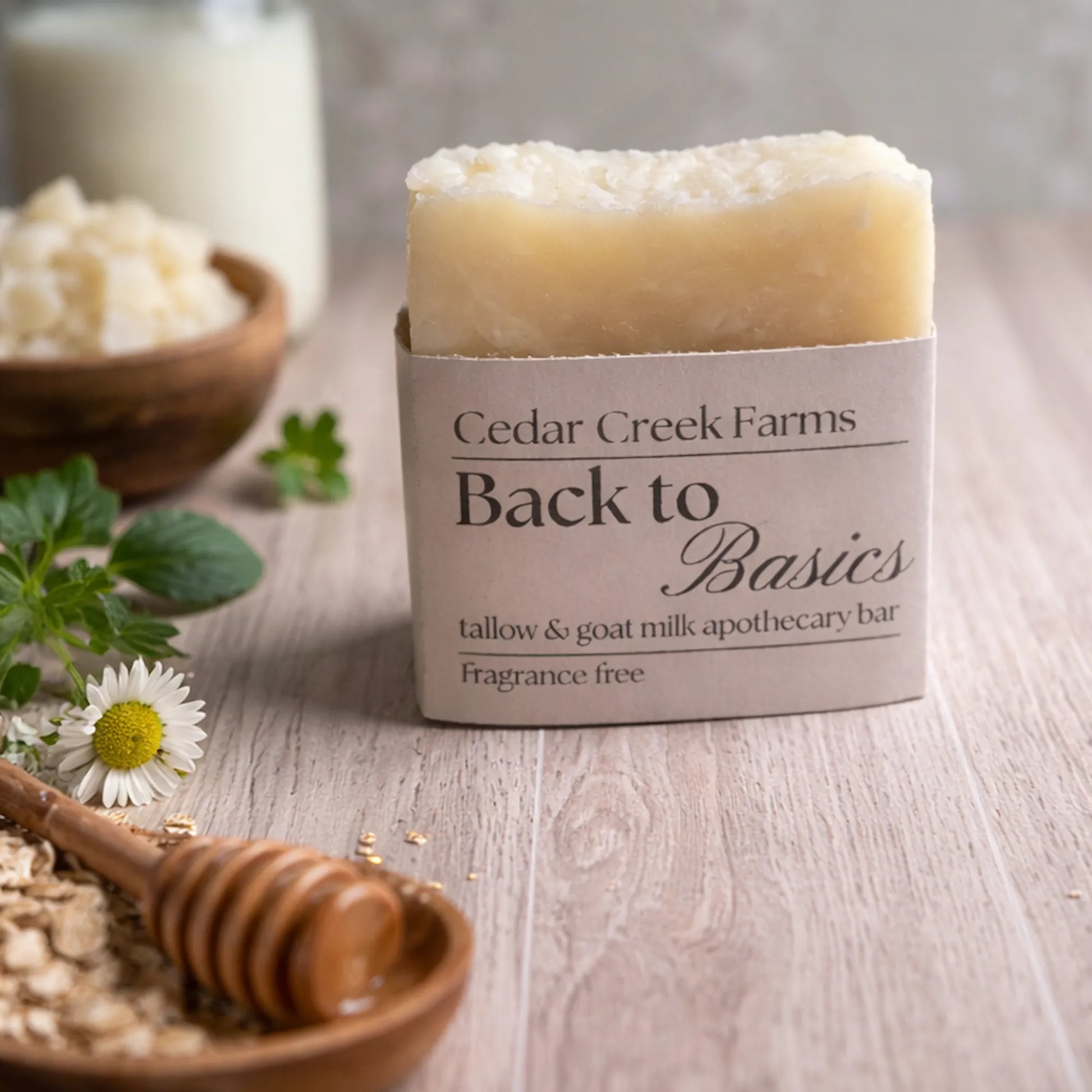 Cedar Creek Farms Back to Basics fragrance free tallow and goat milk soap bar with oats, honey dipper, and chamomile on wooden surface