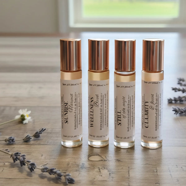 Cedar Creek Farms Botanical Roll-On Fragrance Oil multi scent lineup display showing four glass roller bottles with gold caps and lavender accents on wooden surface