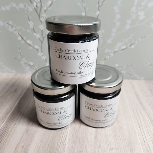 Cedar Creek Farms charcoal and clay black drawing salve jars stacked display natural herbal salve multiple containers