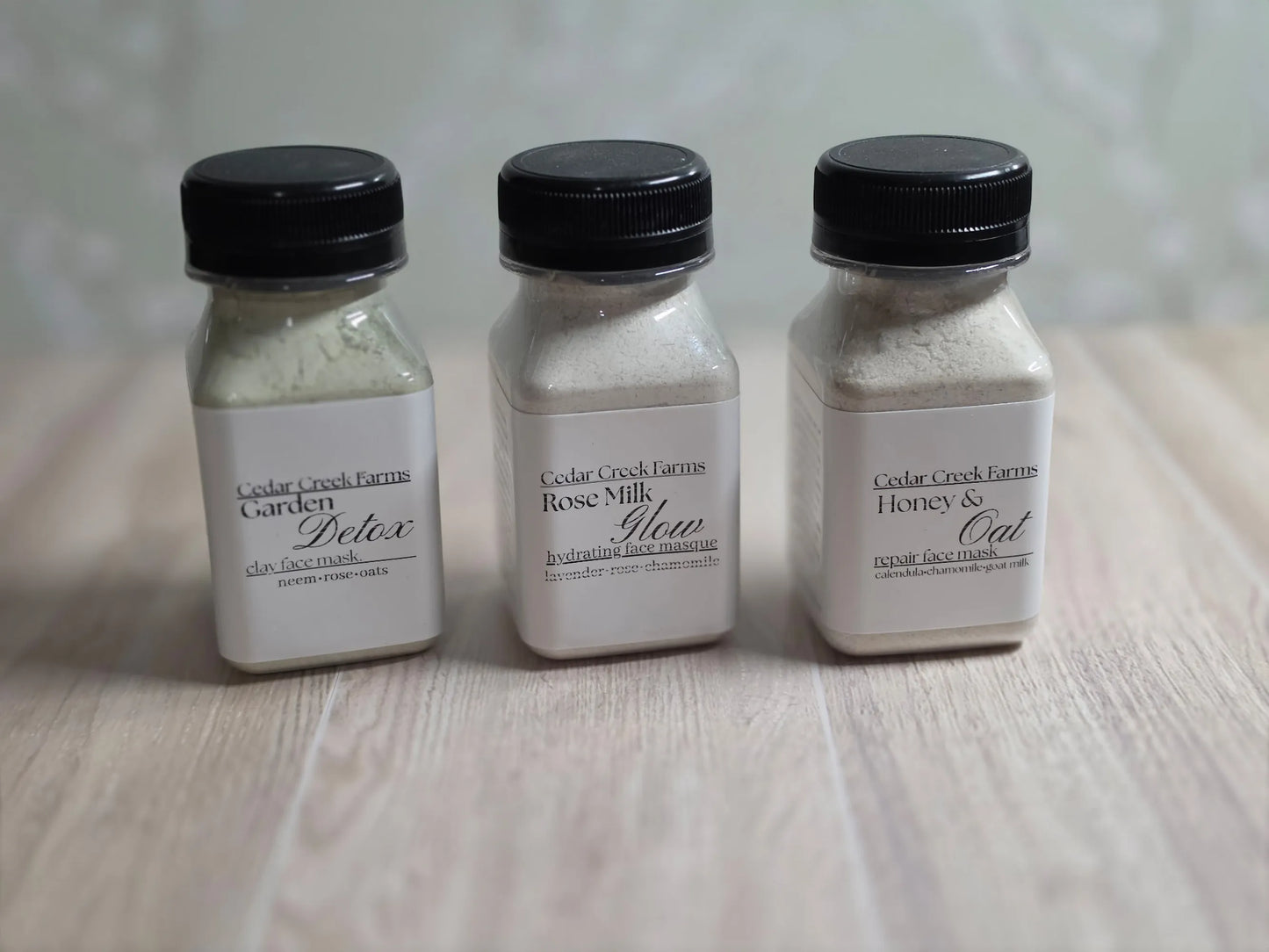 Cedar Creek Farms face mask trio set with three jars of natural clay face masks on wood surface