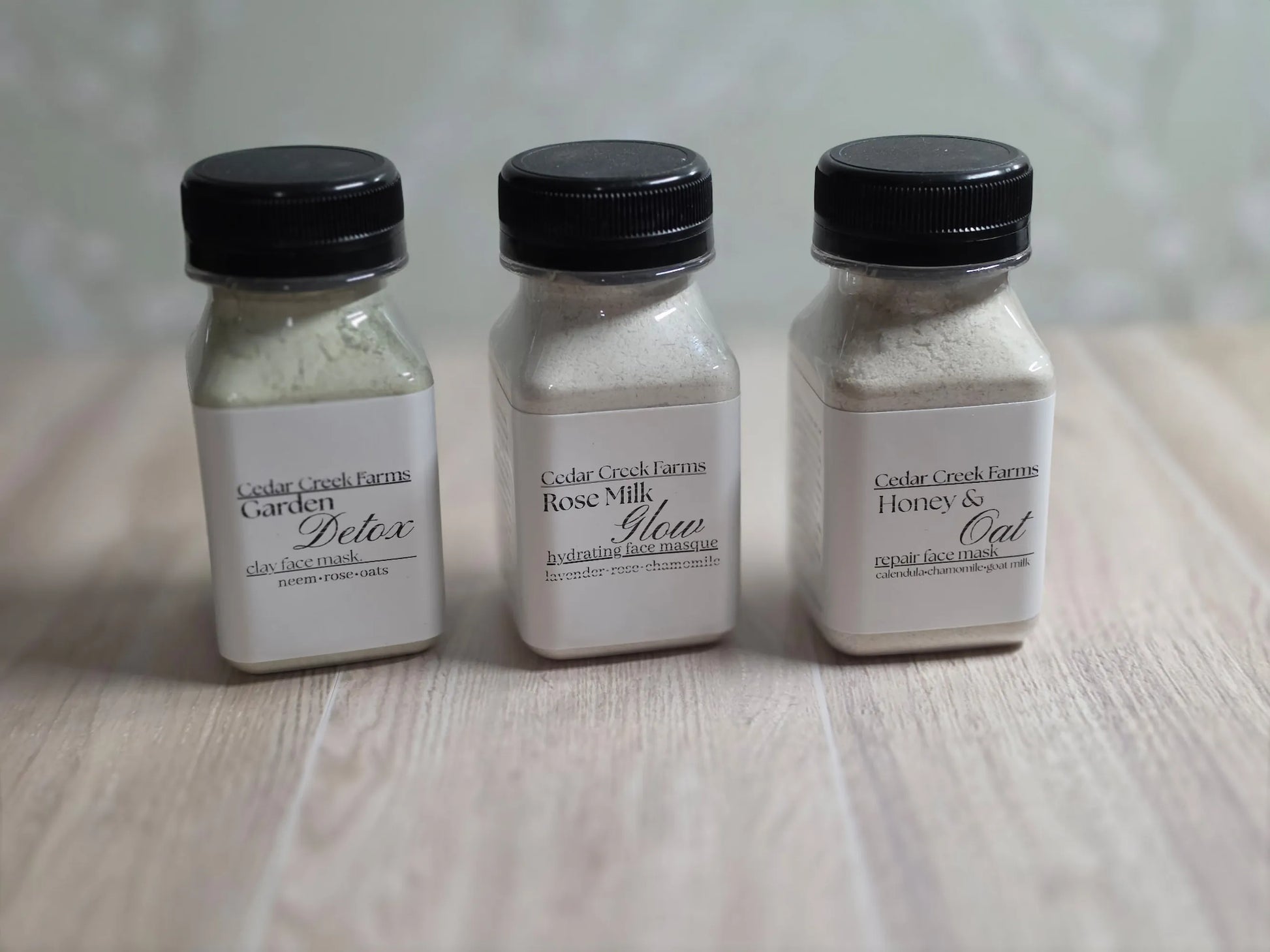 Cedar Creek Farms face mask trio set with three jars of natural clay face masks on wood surface