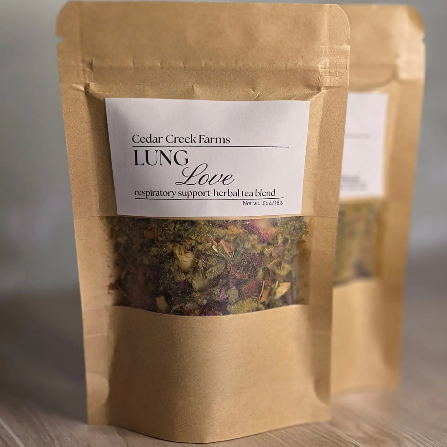 Cedar Creek Farms Lung Love Herbal Tea Blend front packaging close-up showing loose leaf herbal tea inside labeled kraft pouch on wooden surface