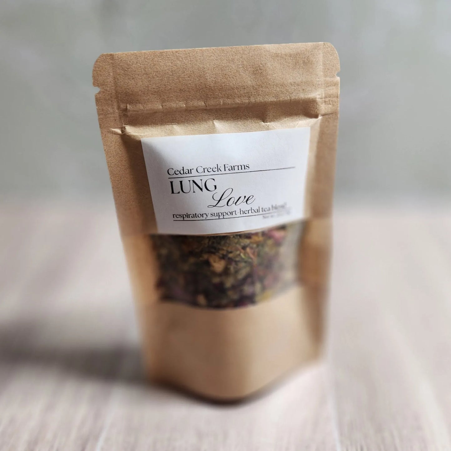 Cedar Creek Farms Lung Love Herbal Tea Blend front packaging product view showing loose leaf herbal tea blend inside labeled kraft pouch on wooden surface