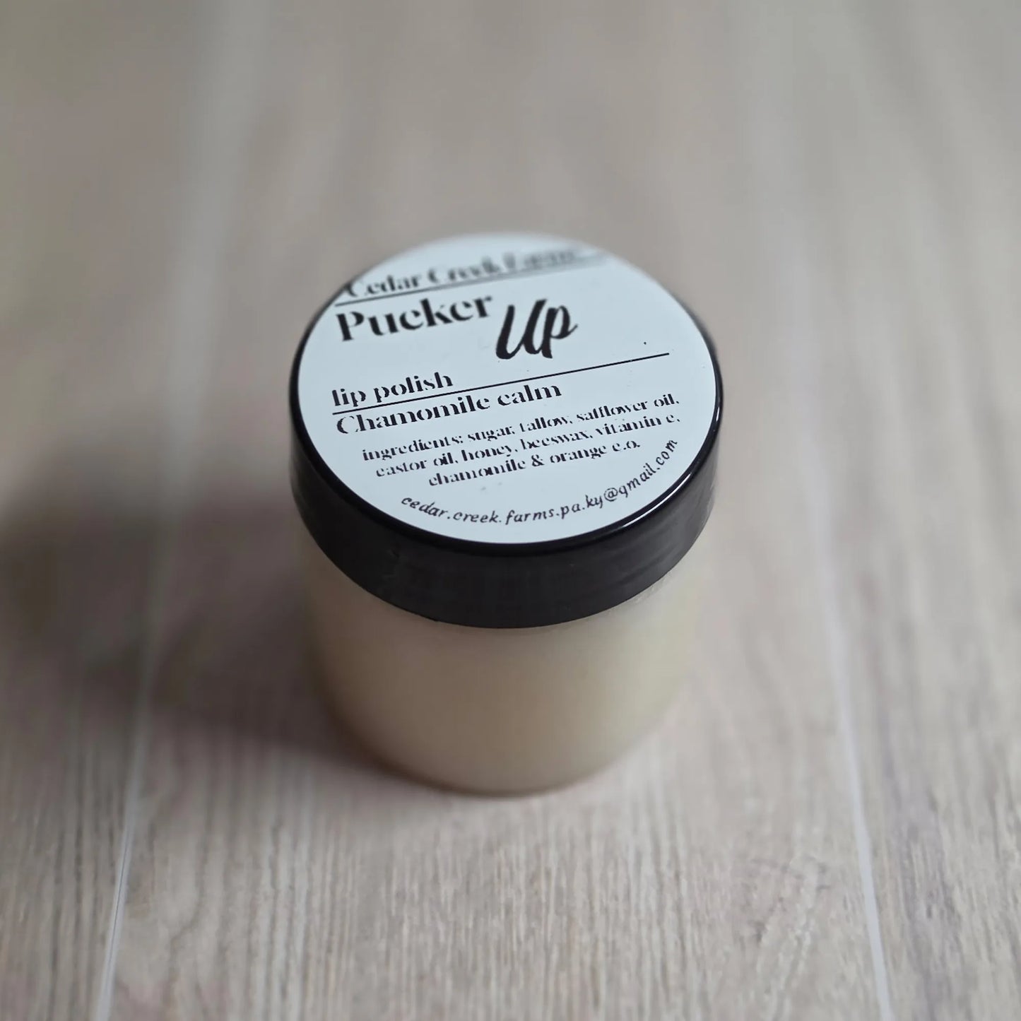 Cedar Creek Farms Pucker Up lip polish chamomile calm jar, natural soothing lip scrub in small container on wood surface
