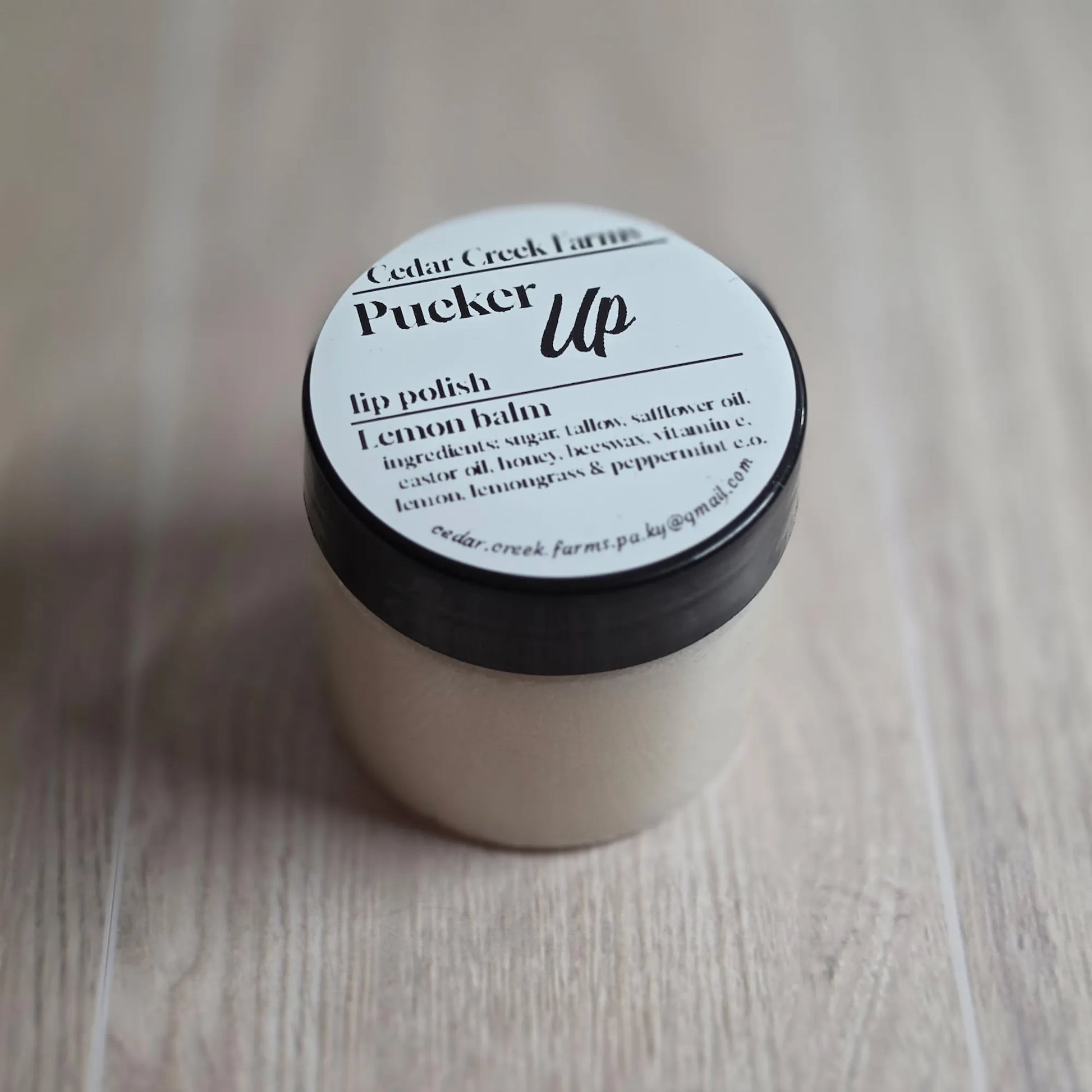 Cedar Creek Farms Pucker Up lip polish lemon balm jar, natural lip scrub in small container on wood surface