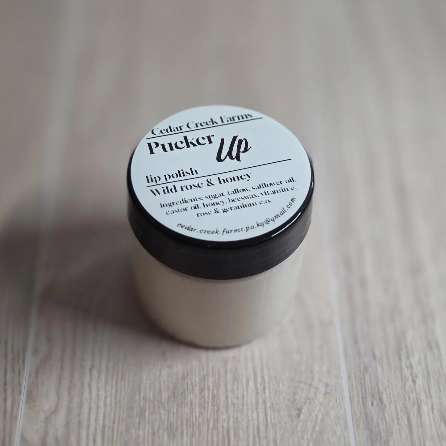 Cedar Creek Farms Pucker Up lip polish wild rose and honey jar, natural lip scrub in small container on wood surface