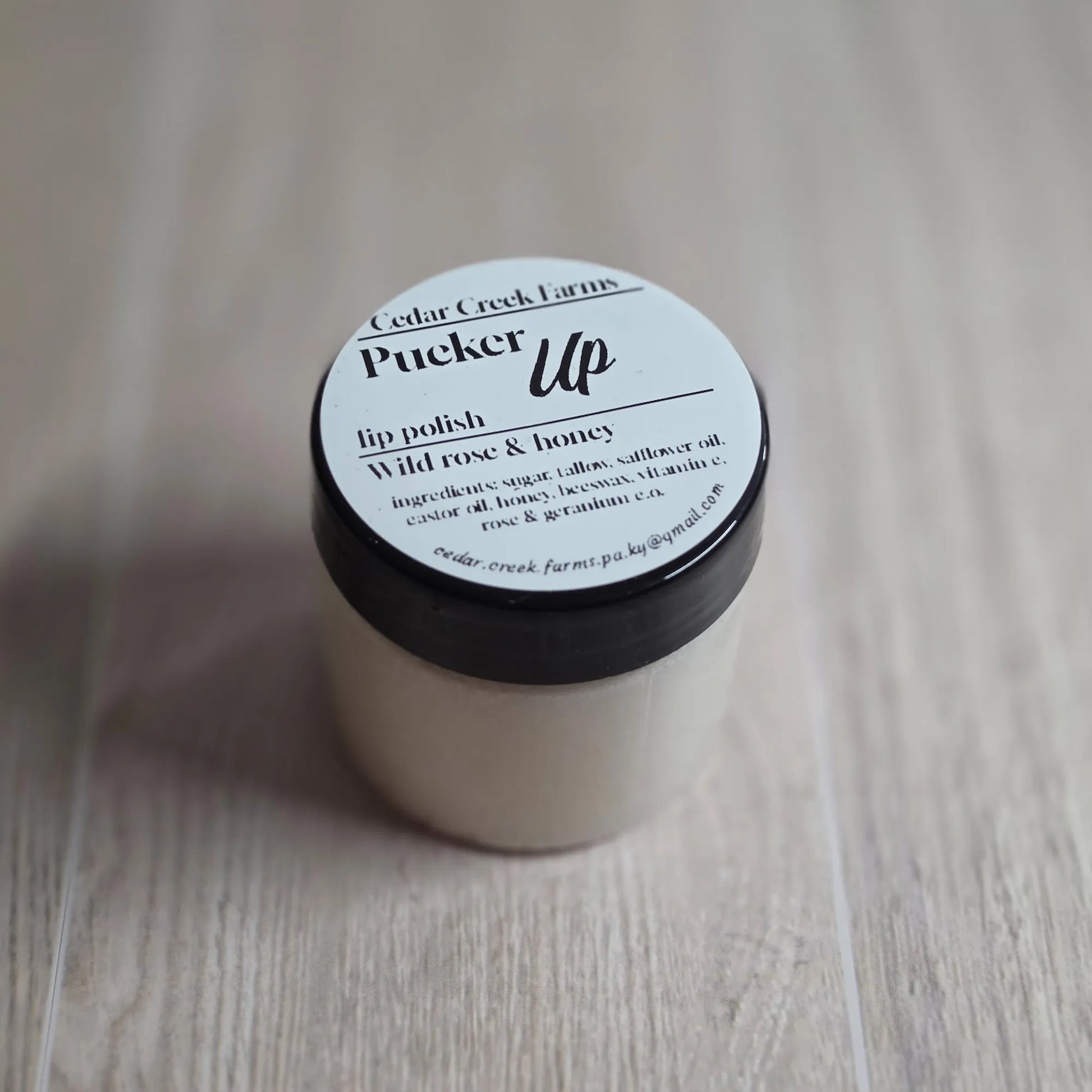 Cedar Creek Farms Pucker Up lip polish wild rose and honey jar, natural lip scrub in small container on wood surface