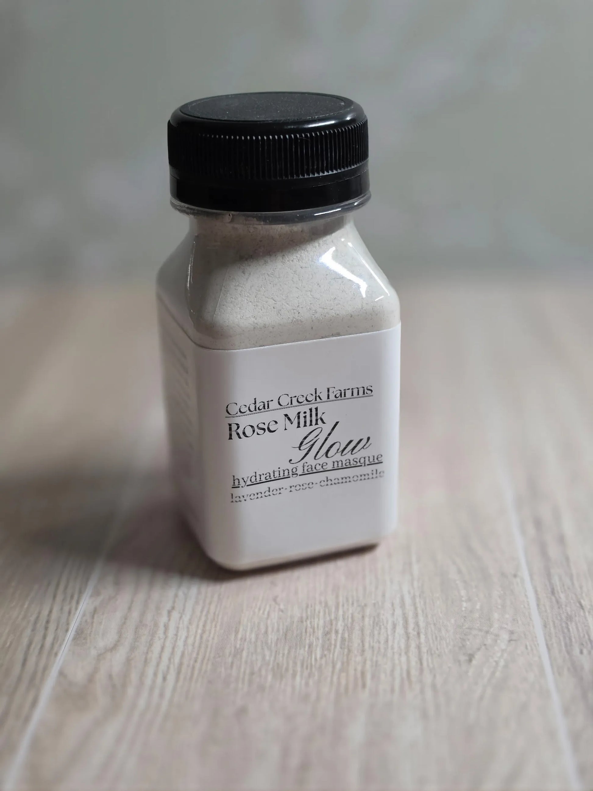 Cedar Creek Farms Rose Milk Glow hydrating face mask jar with black lid, natural glow face mask powder on wood surface