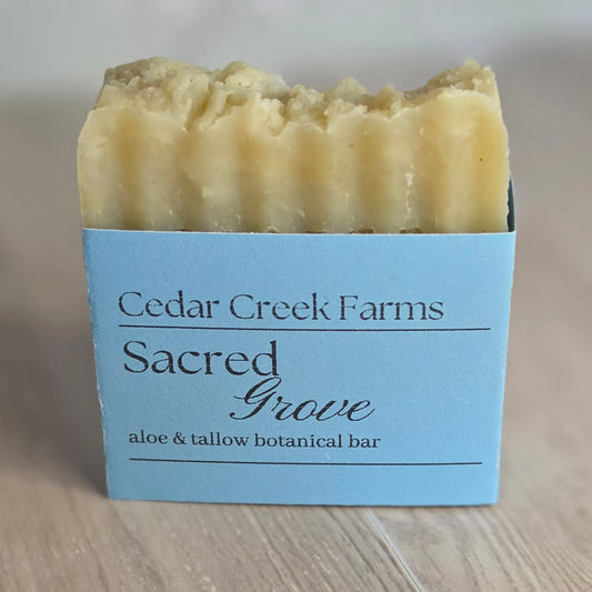 Cedar Creek Farms Sacred Grove Botanical Bar front label close-up showing aloe and tallow botanical soap bar with blue label on wooden surface