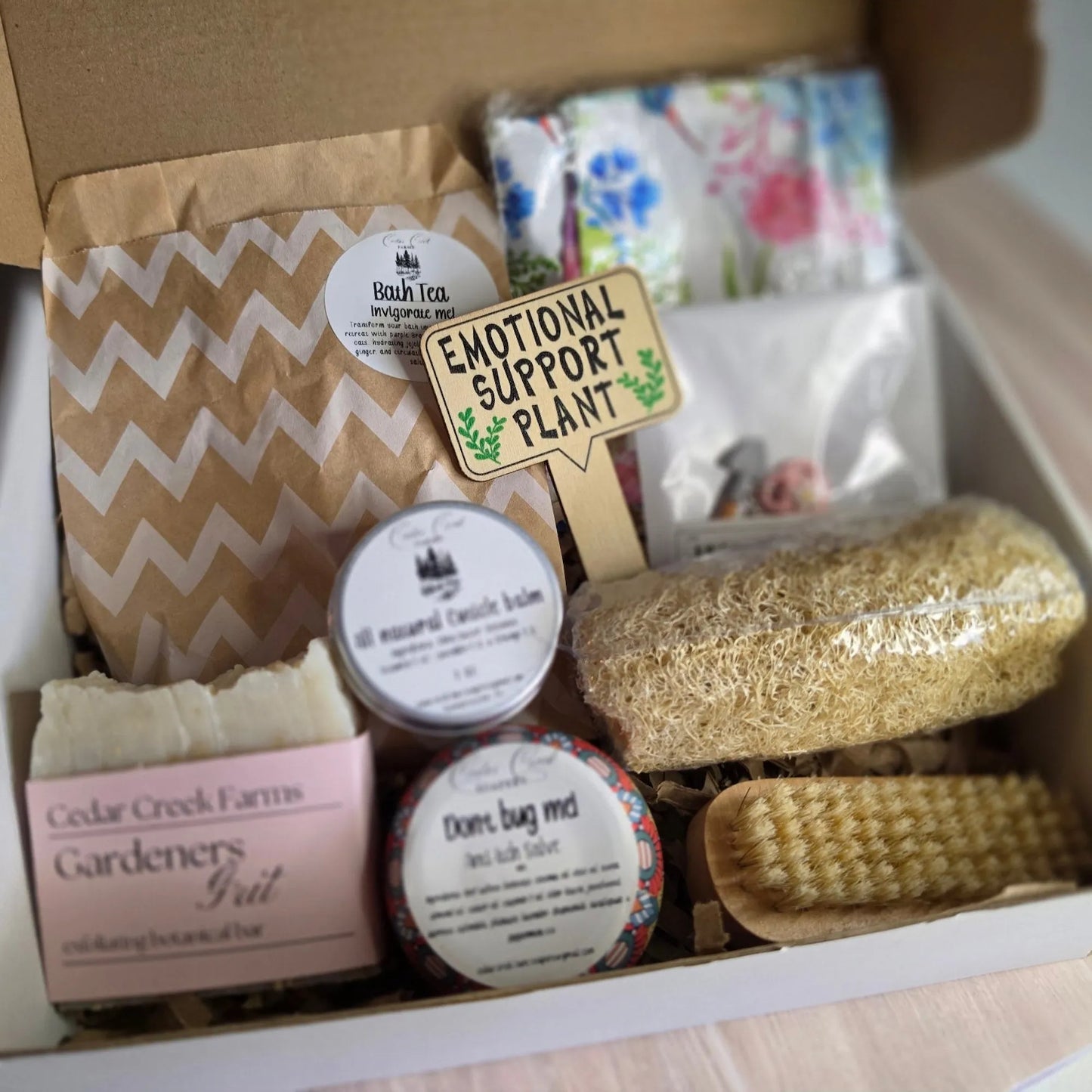 Cedar Creek Farms The Potters Retreat inside open box view showing gardening gift collection for gardeners with soap, salves, brush, loofah, and packaged items arranged in box