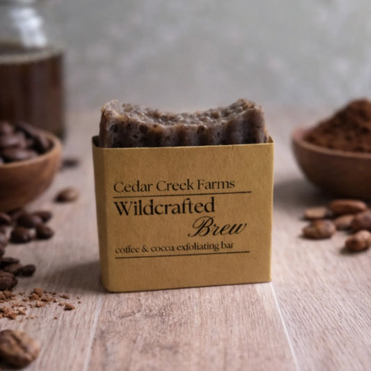 Cedar Creek Farms Wildcrafted Brew coffee and cocoa exfoliating soap bar with coffee beans and natural ingredients on wooden surface